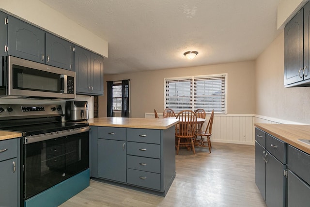 kitchen featuring appliances with stainless steel finishes, light hardwood / wood-style floors, and a textured ceiling