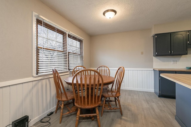 dining space featuring a textured ceiling and light wood-type flooring