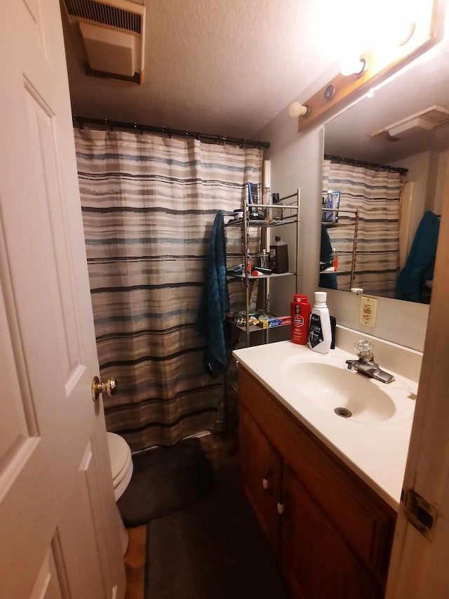 bathroom with vanity, a textured ceiling, toilet, and walk in shower