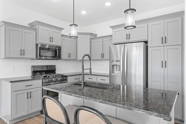 kitchen with stainless steel appliances, hanging light fixtures, and dark stone counters