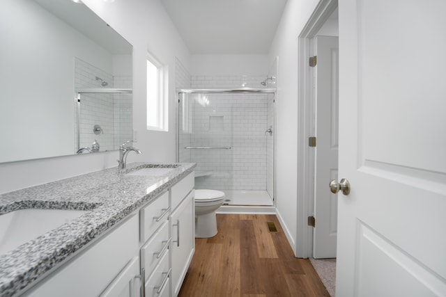 bathroom with hardwood / wood-style flooring, vanity, a shower with door, and toilet