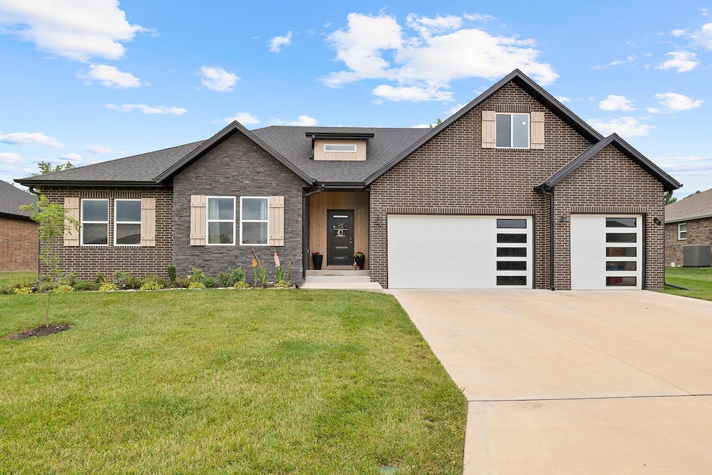 view of front of house with cooling unit, a garage, and a front yard