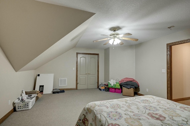 bedroom featuring lofted ceiling, ceiling fan, carpet, a textured ceiling, and a closet