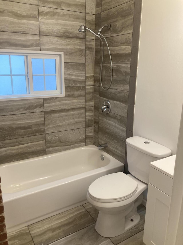 full bathroom featuring tiled shower / bath combo, vanity, and toilet