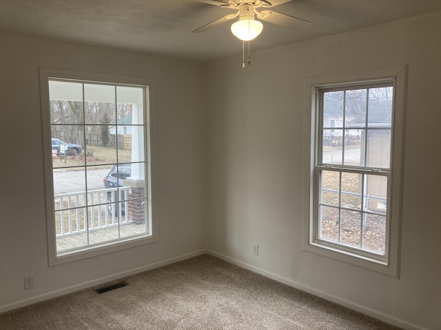 carpeted spare room featuring ceiling fan