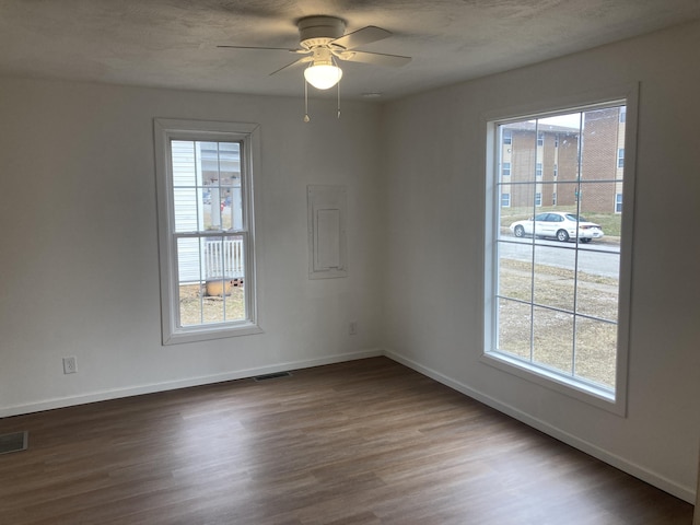 unfurnished room featuring ceiling fan, plenty of natural light, and dark hardwood / wood-style flooring