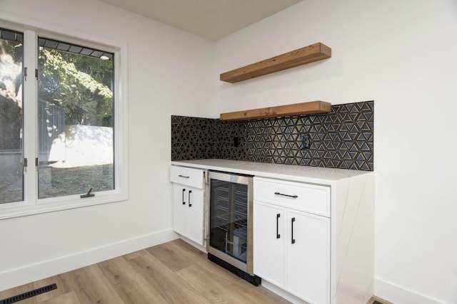 kitchen featuring backsplash, beverage cooler, light hardwood / wood-style floors, and white cabinets