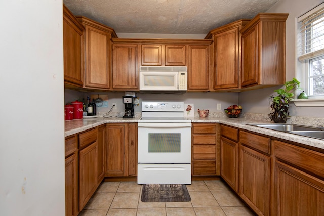 kitchen featuring white appliances, sink, a textured ceiling, and light tile patterned floors