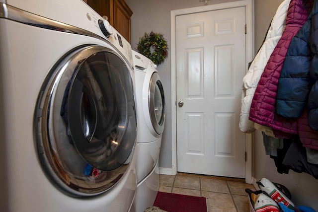 clothes washing area with cabinets, washer and dryer, and light tile patterned flooring