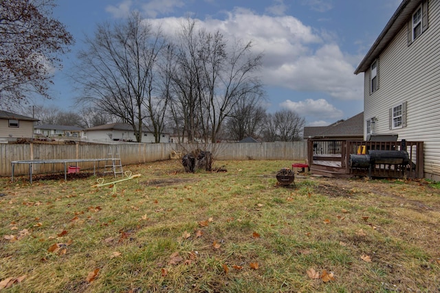 view of yard with a wooden deck and a trampoline