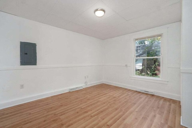 spare room featuring electric panel and light hardwood / wood-style flooring