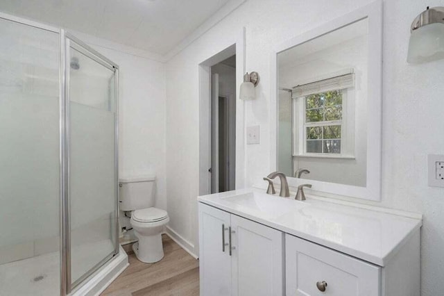 bathroom with wood-type flooring, vanity, ornamental molding, toilet, and a shower with door