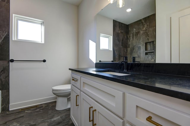 bathroom featuring tiled shower, vanity, and toilet