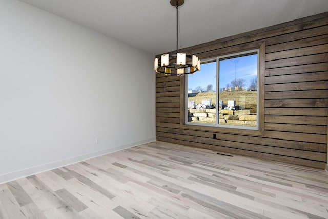 unfurnished dining area with a chandelier and light wood-type flooring