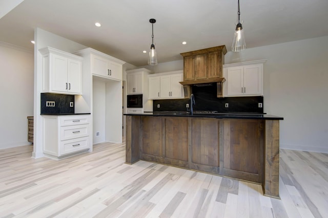 kitchen with pendant lighting, sink, a kitchen island with sink, and white cabinets