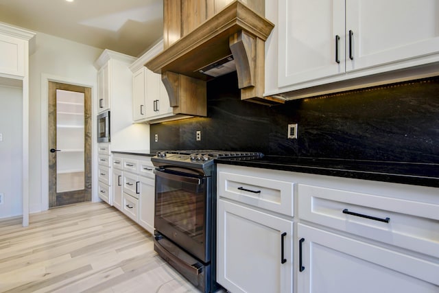 kitchen with premium range hood, range with gas stovetop, white cabinets, light hardwood / wood-style floors, and backsplash