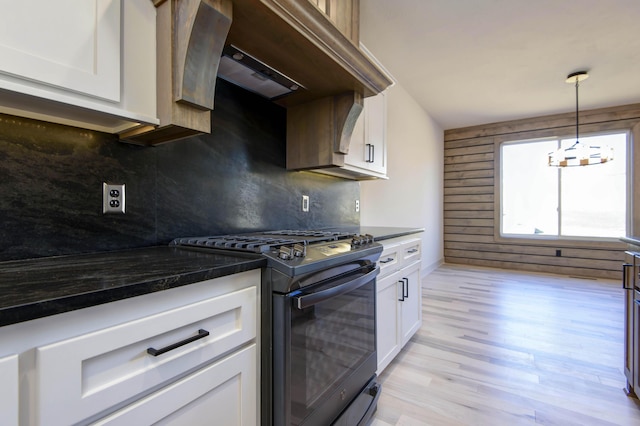 kitchen with white cabinetry, wall chimney range hood, backsplash, and black range with gas cooktop