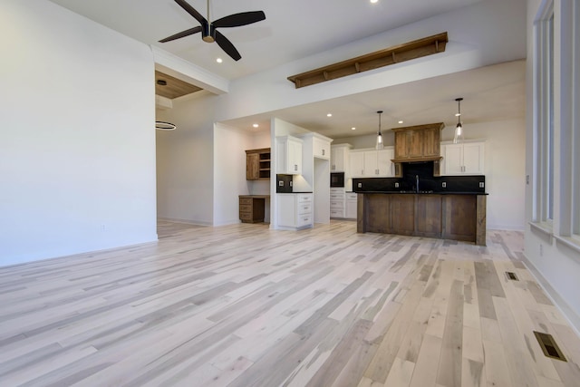 kitchen with white cabinetry, pendant lighting, light hardwood / wood-style floors, and a center island