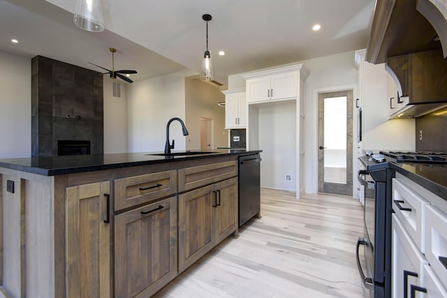 kitchen featuring white cabinetry, sink, stainless steel dishwasher, light hardwood / wood-style floors, and gas stove