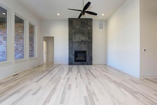 unfurnished living room featuring light hardwood / wood-style floors, a large fireplace, and ceiling fan