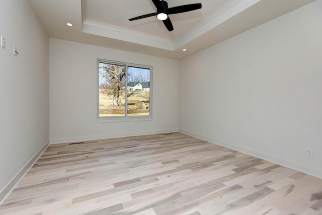 spare room featuring a raised ceiling, ornamental molding, ceiling fan, and light hardwood / wood-style flooring