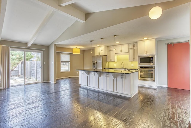 kitchen with white cabinetry, a center island, appliances with stainless steel finishes, pendant lighting, and a barn door