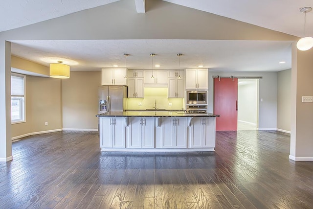 kitchen with white cabinetry, appliances with stainless steel finishes, a kitchen island with sink, and decorative light fixtures