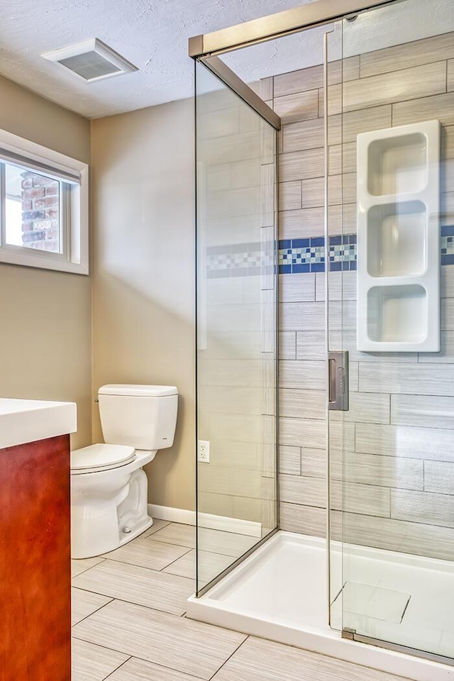 bathroom with toilet, vanity, a textured ceiling, and walk in shower