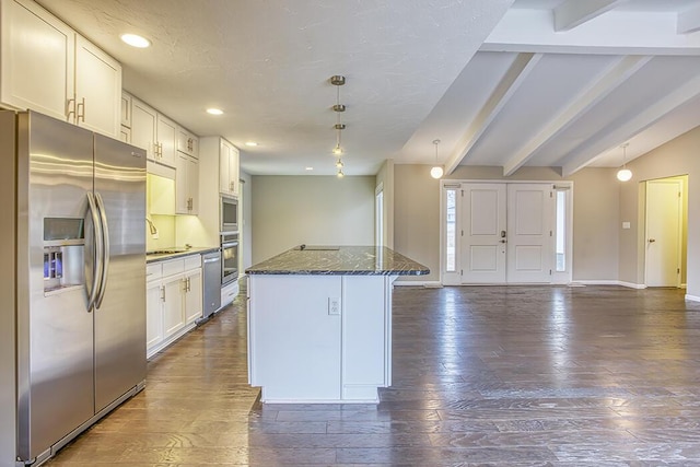 kitchen featuring white cabinetry, stainless steel appliances, a kitchen island, and dark stone counters