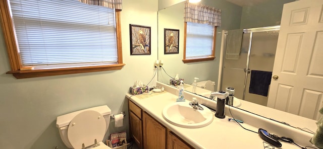 bathroom featuring vanity, a shower with door, and toilet