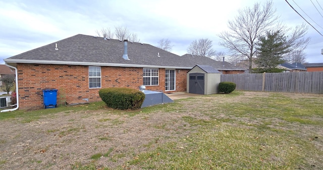 back of property featuring a yard, central air condition unit, and a storage unit