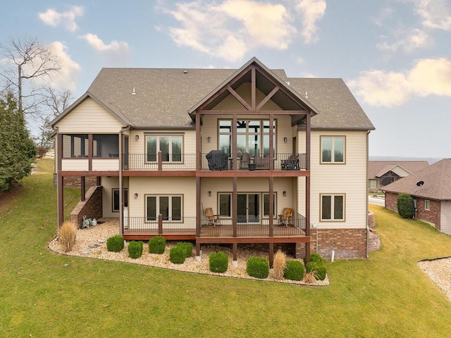 back of property with a balcony, a sunroom, and a lawn