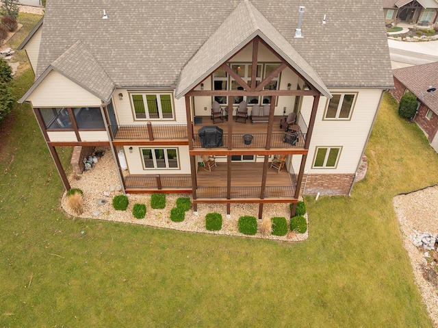 back of property with a deck, a sunroom, and a lawn