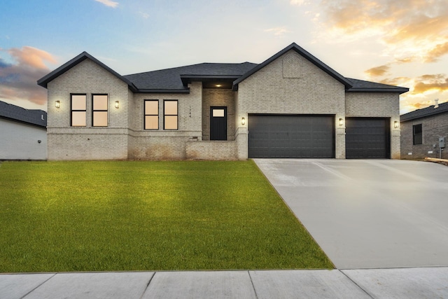 view of front facade with a garage, concrete driveway, brick siding, and a front yard