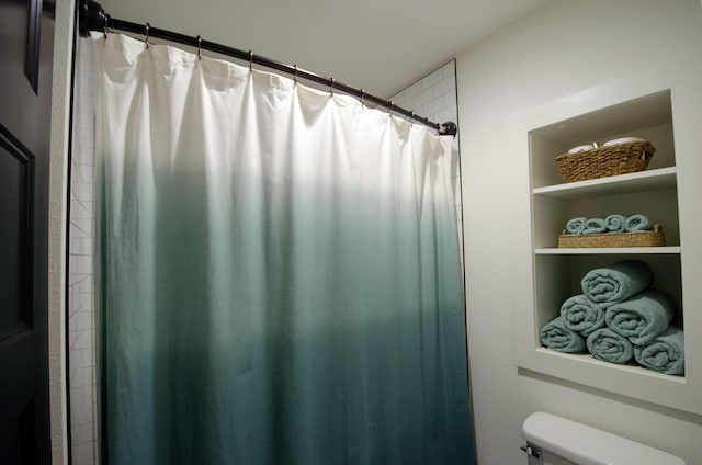 bathroom featuring toilet, built in shelves, and a shower with shower curtain