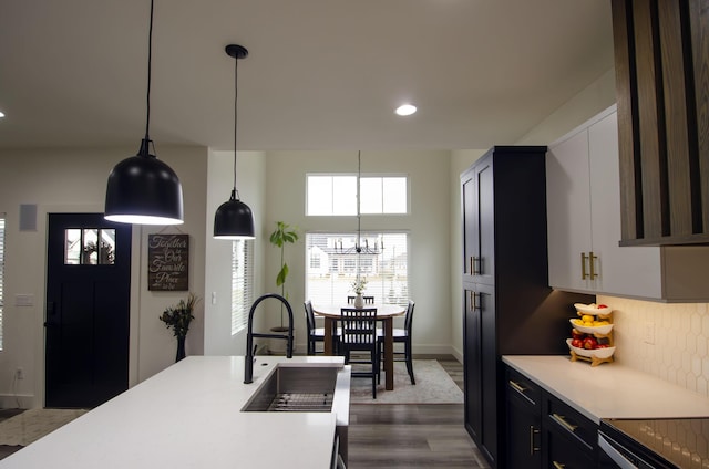 kitchen featuring pendant lighting, tasteful backsplash, sink, dark wood-type flooring, and an inviting chandelier