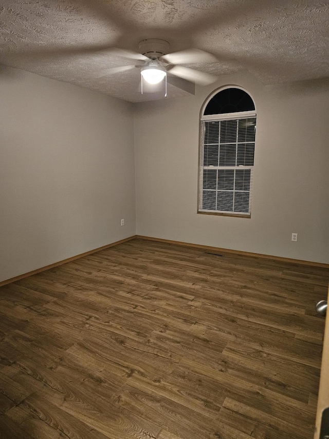 empty room featuring dark hardwood / wood-style floors, a textured ceiling, and ceiling fan