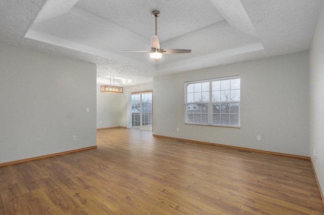 unfurnished room with a raised ceiling, hardwood / wood-style floors, and a textured ceiling