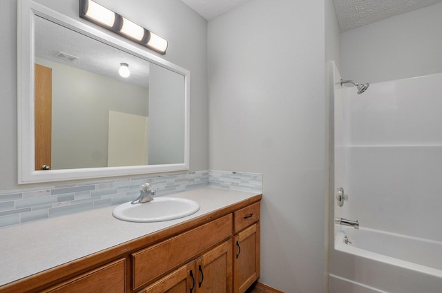 bathroom featuring vanity, shower / bathing tub combination, decorative backsplash, and a textured ceiling