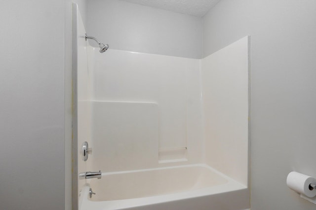 bathroom featuring tub / shower combination and a textured ceiling