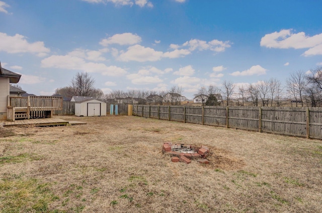 view of yard featuring a storage unit, a deck, and a fire pit