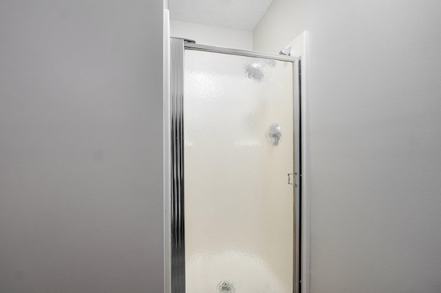 bathroom with a shower with door and a textured ceiling