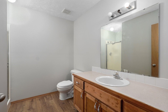 bathroom with a shower with door, hardwood / wood-style floors, vanity, a textured ceiling, and toilet