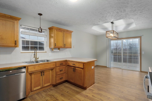 kitchen with sink, light hardwood / wood-style flooring, decorative light fixtures, stainless steel dishwasher, and kitchen peninsula