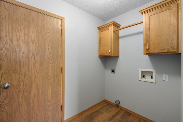 clothes washing area featuring hardwood / wood-style floors, cabinets, washer hookup, electric dryer hookup, and a textured ceiling