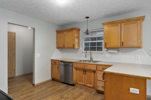 kitchen featuring sink, tasteful backsplash, light hardwood / wood-style floors, decorative light fixtures, and stainless steel dishwasher