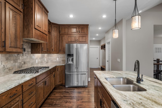 kitchen featuring stainless steel appliances, light stone countertops, sink, and pendant lighting