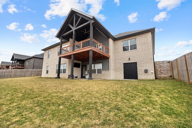 rear view of house with ceiling fan, a deck, and a lawn