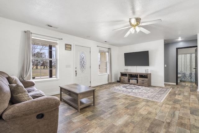 living room with hardwood / wood-style flooring, ceiling fan, and a textured ceiling