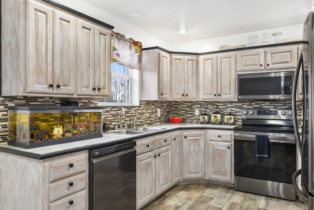 kitchen featuring light brown cabinetry, sink, light hardwood / wood-style flooring, stainless steel appliances, and backsplash